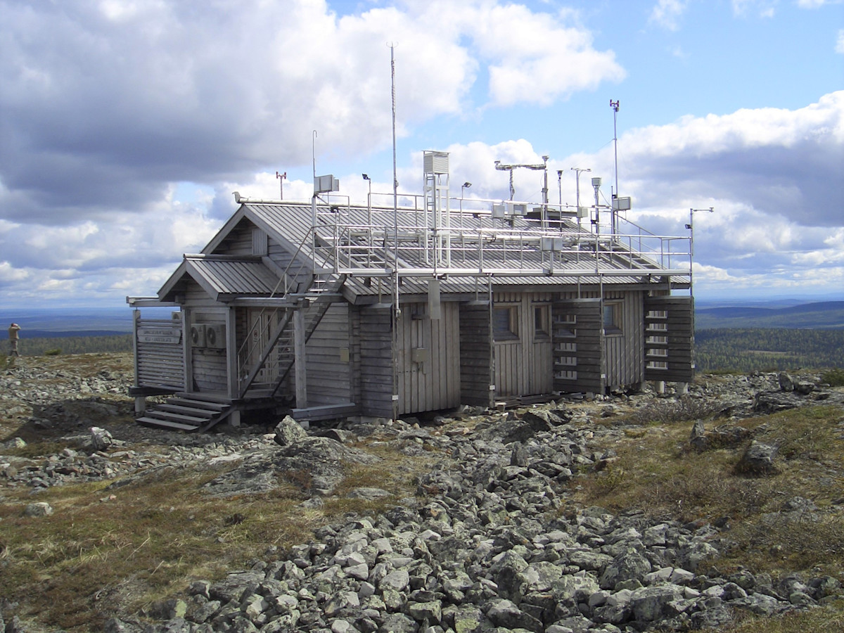 Small log building on the top of a mountain, on the roof measuring equipments