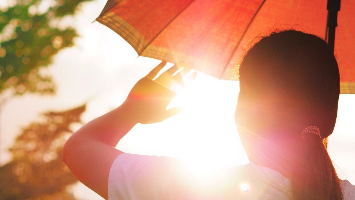 A girl with an umbrella looking at the sun.