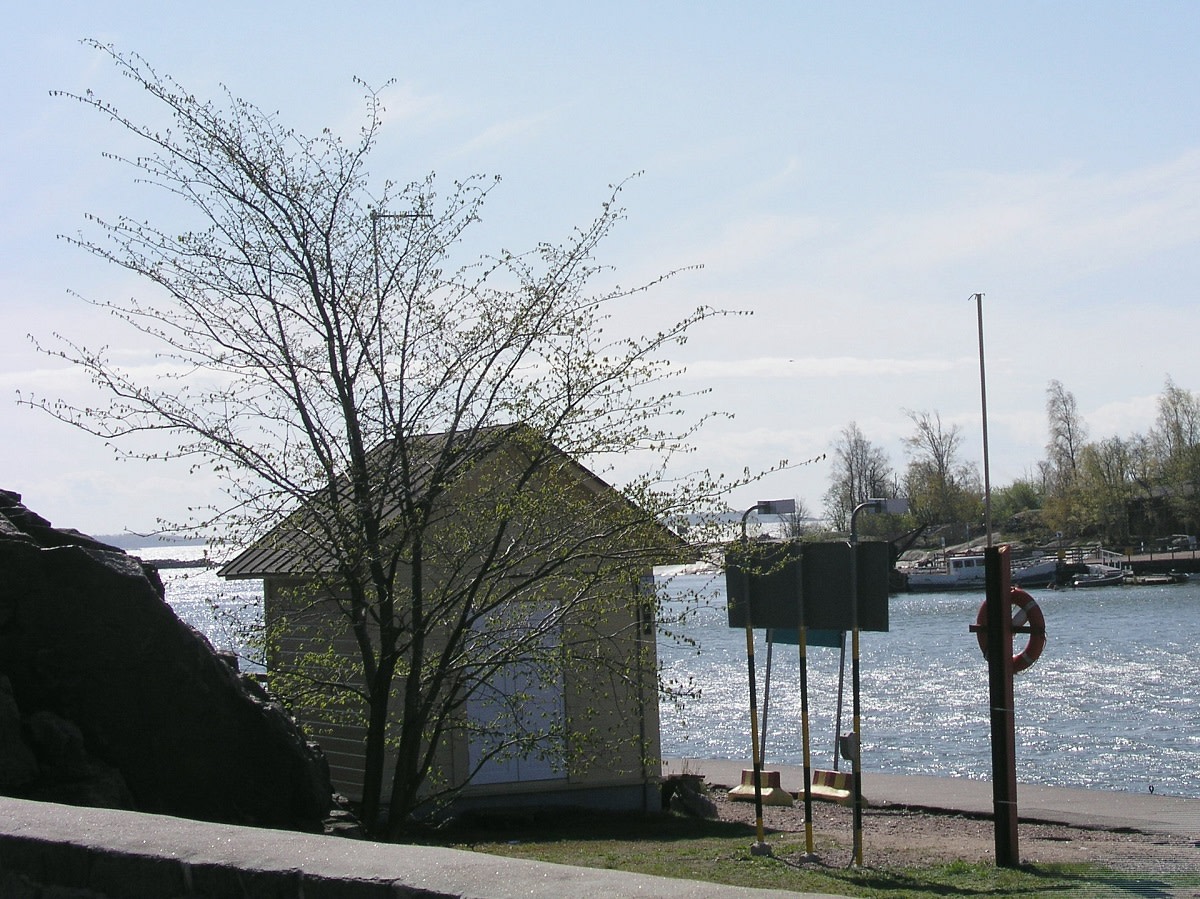 A small storehouse looking building on the shore.