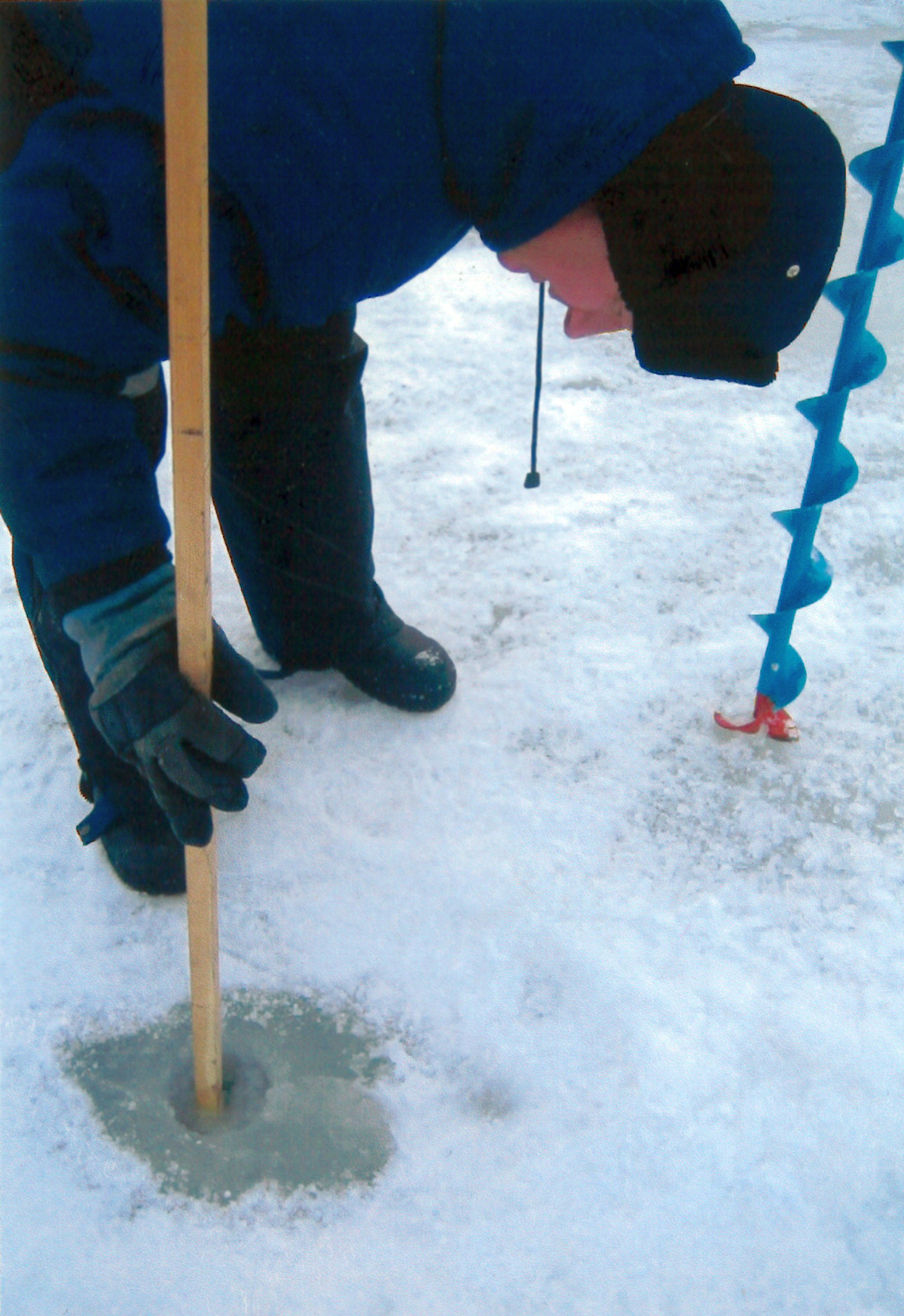 A man has a measurement stick in a drillhole.