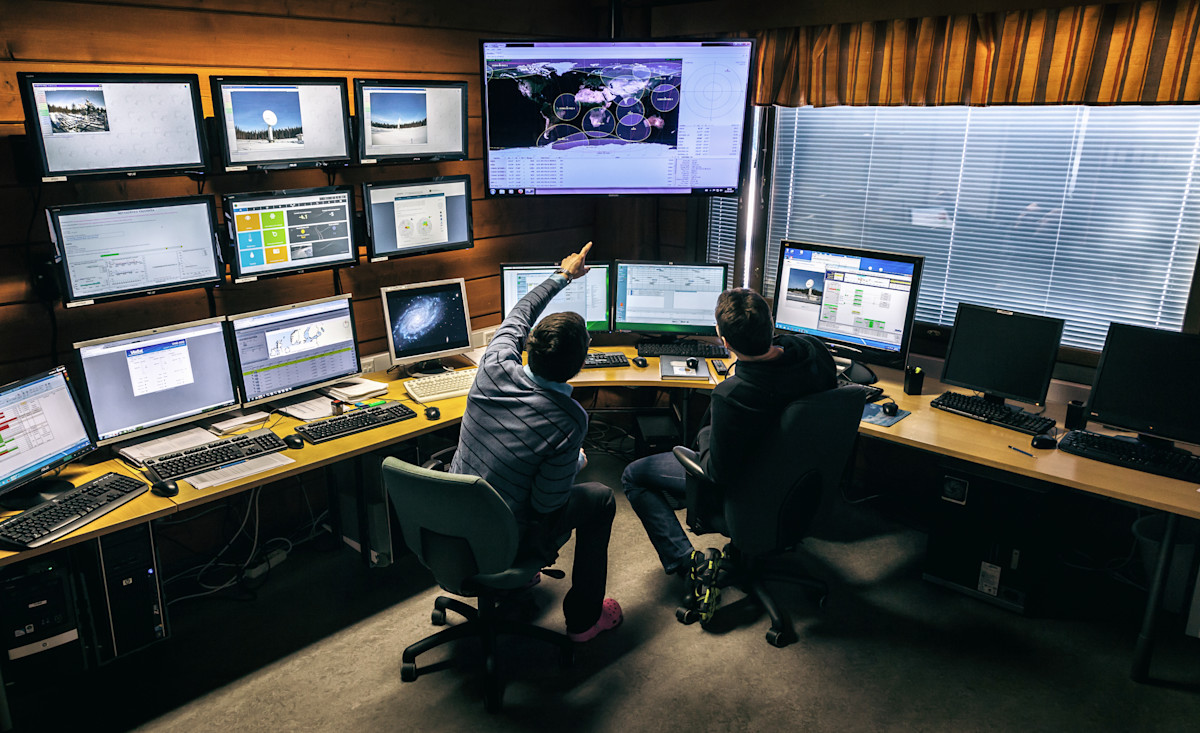Picture with two people sitting in front of monitors.