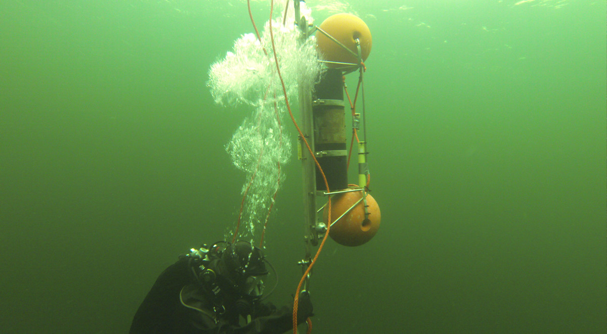 A diver under water next to measuring equipment.