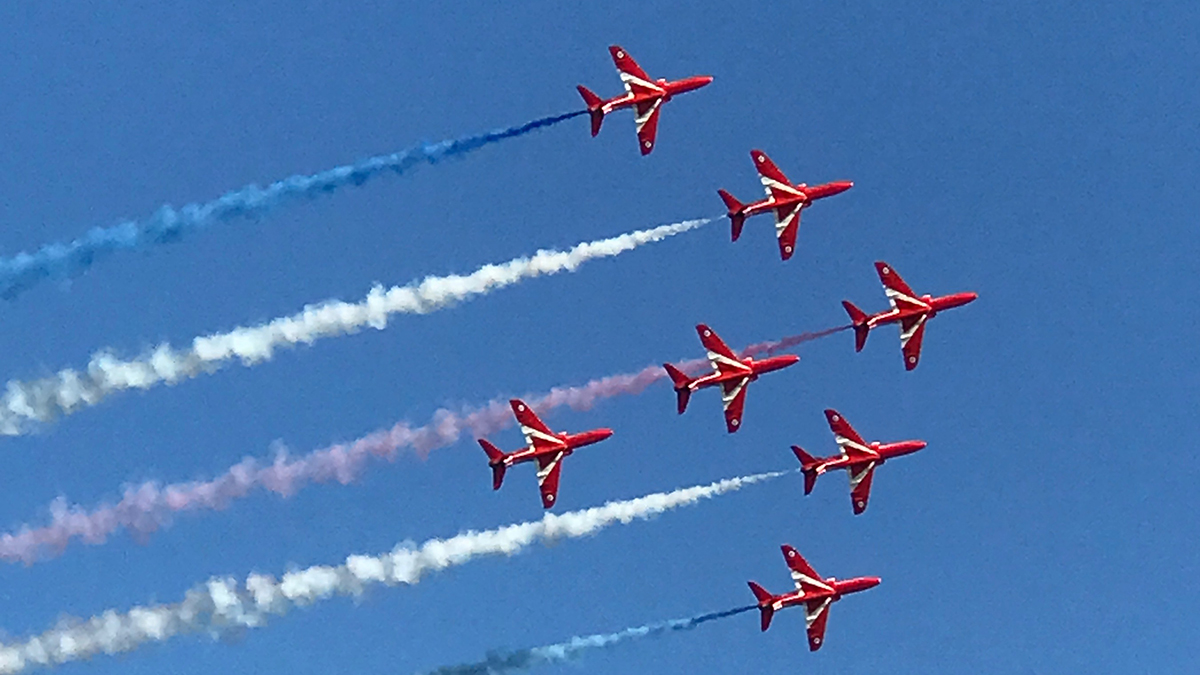7 Red Arrow -planes flying on a blue sky.