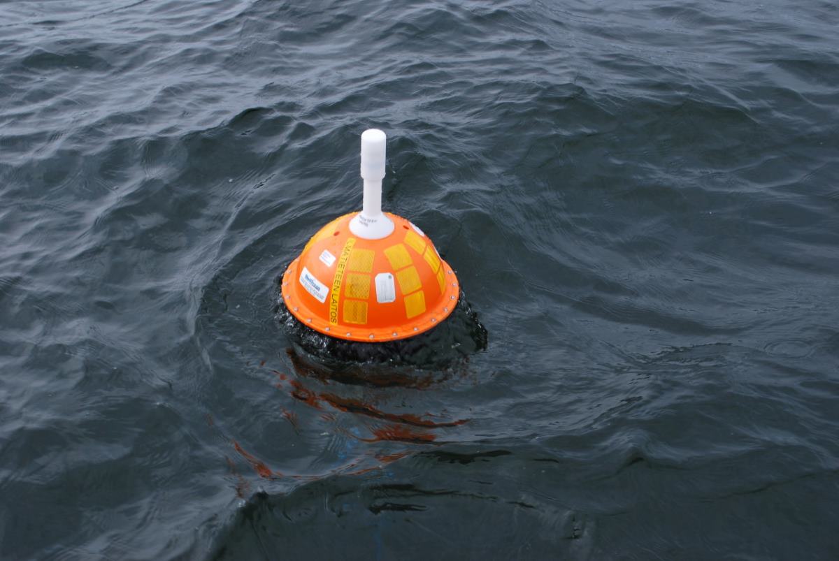 Orange buoy with a white antenna in the sea.