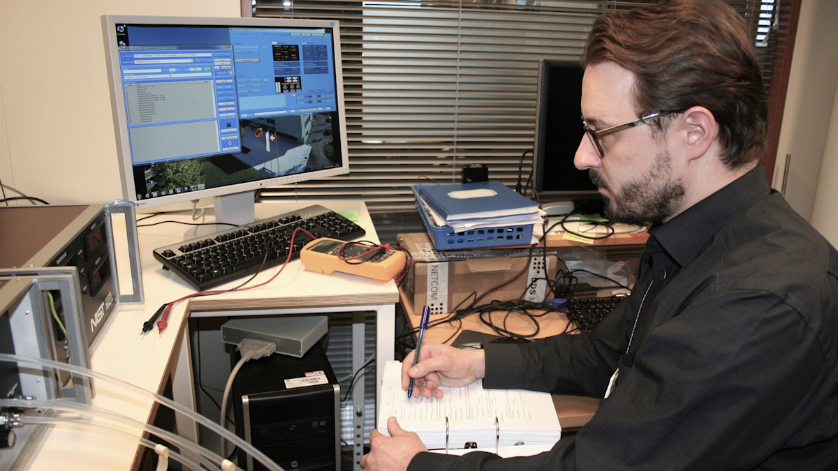 Laboratory worker sitting in front of a computer and making notes, instruments