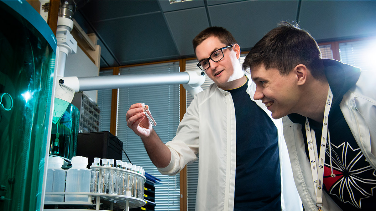Laboratory workers inspecting a sample tube.